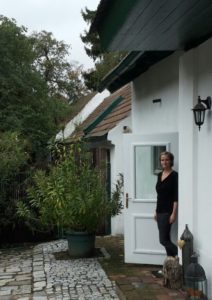 Innenhof eines Winzerhofs, Pflastersteinboden und Oleander, eine Frau steht in einer offenen Tür.